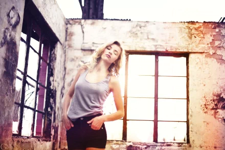 A woman named Rachel Ann Yampolsky poses confidently in an abandoned space, with sunlight streaming through large windows, creating a striking HD desktop wallpaper.