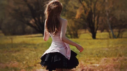 A woman in a flowing skirt stands in a serene outdoor setting, with her back to the viewer, surrounded by greenery. This HD image makes a striking desktop wallpaper.