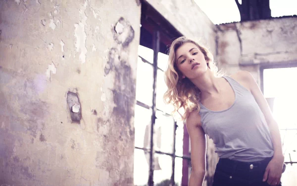 HD PC desktop wallpaper featuring a woman, Rachel Ann Yampolsky, posing gracefully in a softly lit, rustic indoor setting with worn walls and large windows.