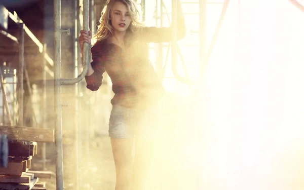 HD PC desktop wallpaper of a woman in an industrial loft, bathed in golden light and haze, standing by beams and pipes with dramatic high-contrast lighting.