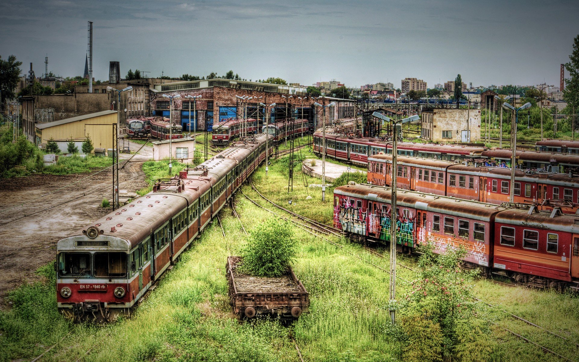 A high-definition HDR photograph of a vibrant train yard, featuring multiple trains and lush greenery, makes an engaging desktop wallpaper and background.
