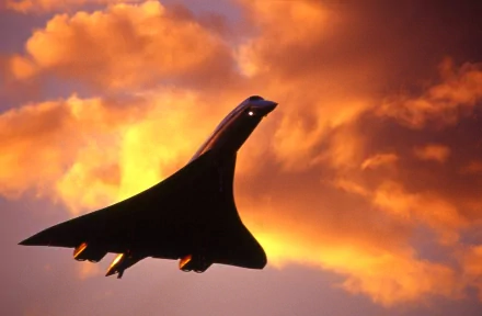 HD desktop wallpaper featuring a sleek aircraft silhouetted against a dramatic orange and yellow sunset sky.