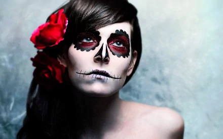 A striking artistic depiction of a woman with sugar skull makeup, featuring red accents and a flower in her hair, serves as a vivid HD desktop wallpaper and background.