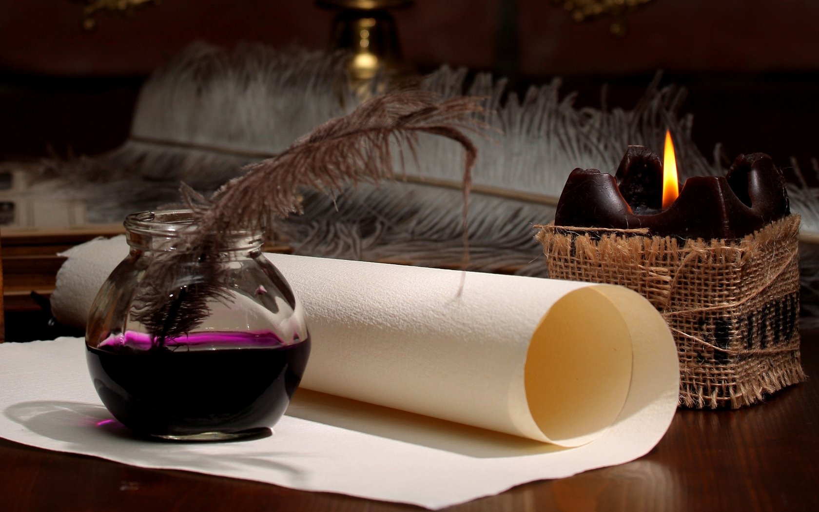 A still life composition featuring a glass ink jar with a feather quill, a rolled parchment, and a candle in a burlap holder, set against a warm, inviting background. HD desktop wallpaper.