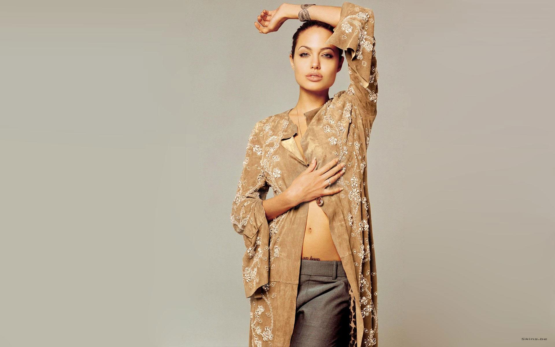 HD PC desktop wallpaper featuring celebrity Angelina Jolie posing gracefully in a sheer, embroidered beige jacket against a neutral background.