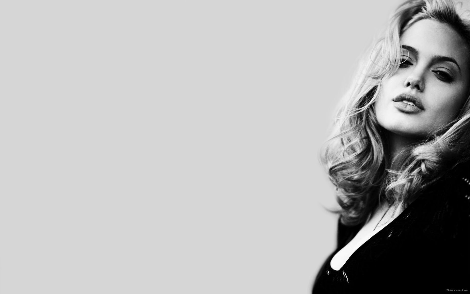A striking black-and-white HD desktop wallpaper featuring celebrity Angelina Jolie, showcasing her captivating gaze and elegant hairstyle against a minimalist background.