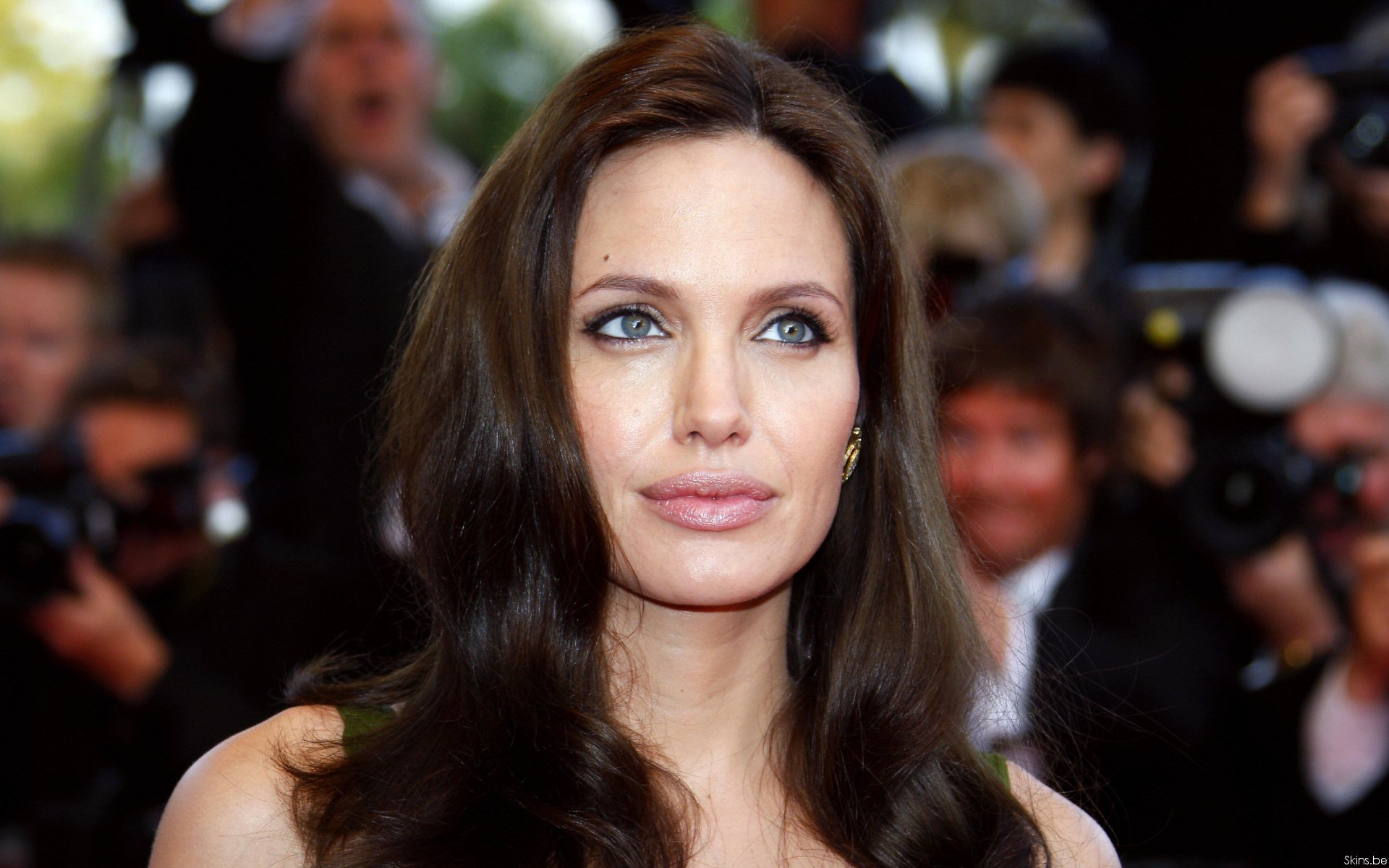 HD PC desktop wallpaper featuring a close-up of celebrity Angelina Jolie with long dark hair and blue eyes at a public event.