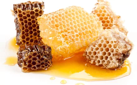 A close-up of honeycomb pieces drizzled with golden honey, showcasing the natural texture and richness of this sweet treat. Suitable as a HD PC desktop wallpaper and background.