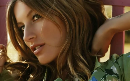 Gisele Bündchen poses gracefully in this HD desktop wallpaper, showcasing her stunning features and style against a vibrant, natural backdrop.