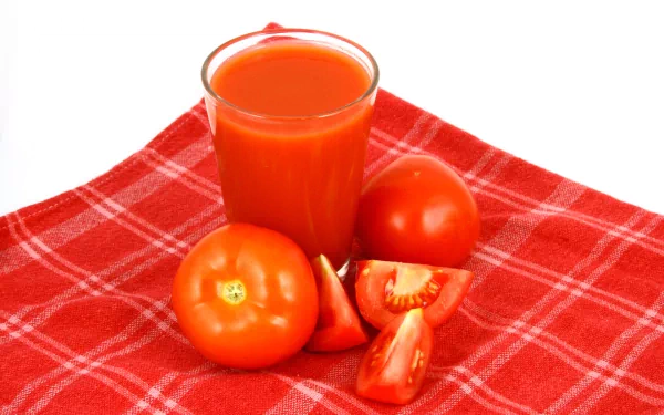 HD PC desktop wallpaper featuring fresh whole and sliced tomatoes with a glass of tomato juice on a red checkered cloth.