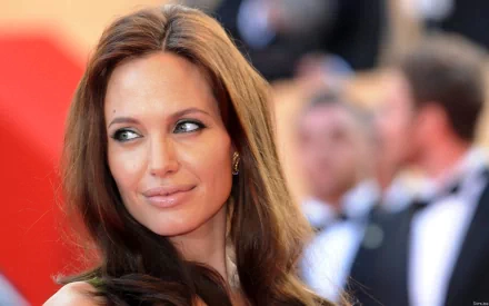 HD PC desktop wallpaper featuring a close-up of celebrity Angelina Jolie with her hair down and a blurred red carpet background.