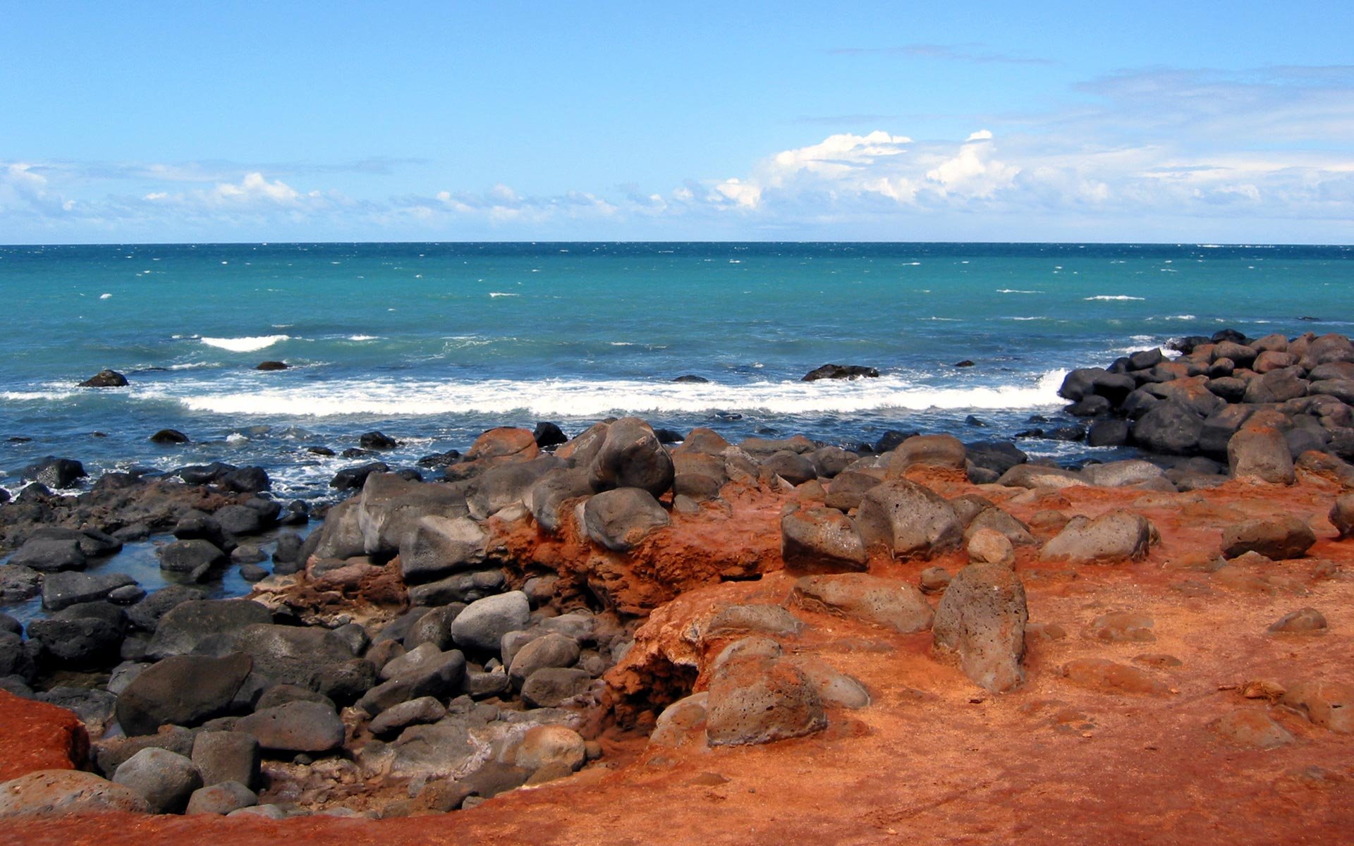 HD PC desktop wallpaper featuring a vibrant ocean view with rocky shoreline under a partly cloudy sky, showcasing the beauty of nature.