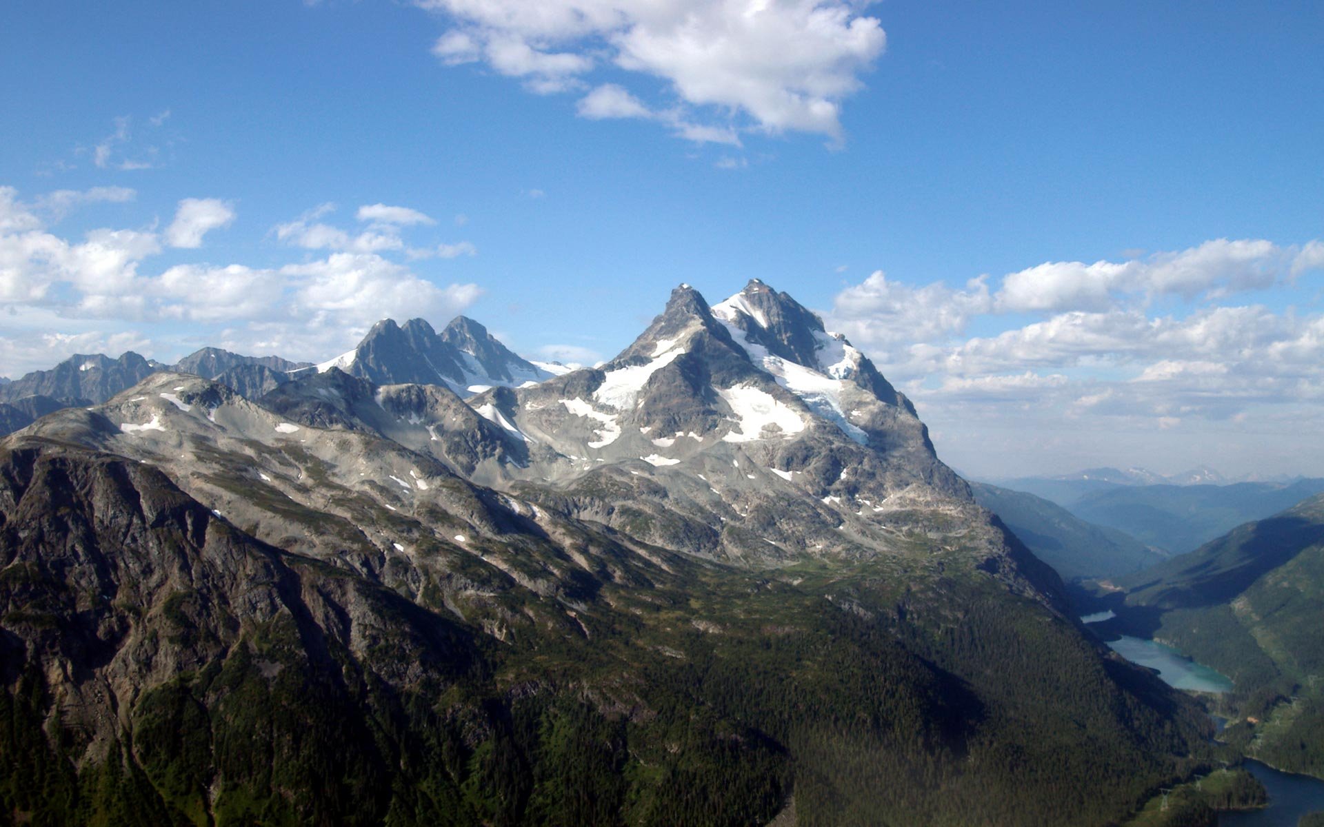HD PC desktop wallpaper featuring a stunning mountain range under a blue sky with scattered clouds, showcasing the beauty of nature.