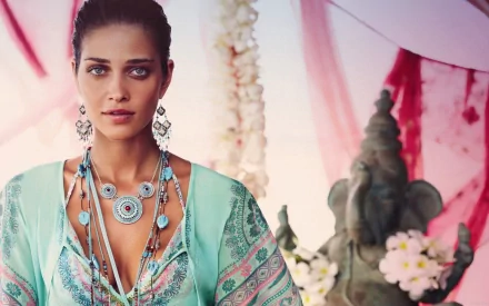 HD desktop wallpaper featuring Ana Beatriz Barros wearing a turquoise patterned outfit with layered jewelry, set against a soft, decorative background.