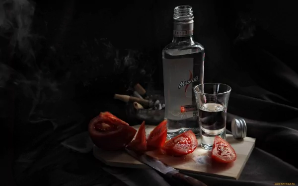 A dark, moody desktop wallpaper featuring a bottle of liquor, a shot glass, and sliced tomatoes arranged on a cutting board, creating a striking food and drink composition.