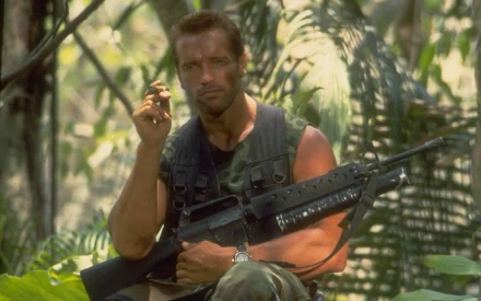 Arnold Schwarzenegger in a still from the movie *Predator*, showcasing his iconic role in a dense jungle setting. This high-definition image serves as a striking desktop wallpaper.