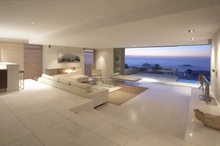 A spacious, modern interior featuring a stylish sofa and large windows offering a stunning view of the ocean, designed as a 4K Ultra HD PC desktop wallpaper and background.