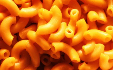 HD desktop wallpaper featuring a close-up of vibrant orange elbow pasta, highlighting its curved shapes and smooth texture.