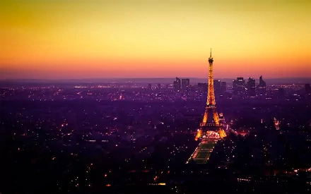 A stunning HD wallpaper of Paris at dusk, showcasing the illuminated Eiffel Tower amidst the city's skyline. The warm colors of the setting sun cast a magical glow over the man-made landscape.