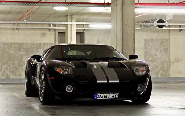 HD PC desktop wallpaper featuring a sleek black Ford GT with silver racing stripes parked in an industrial-style concrete garage.