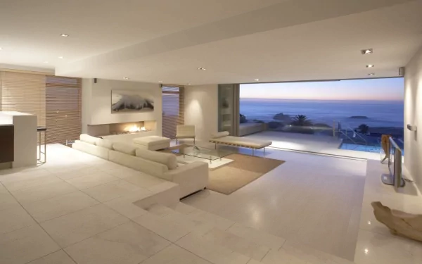 A spacious, modern interior featuring a stylish sofa and large windows offering a stunning view of the ocean, designed as a 4K Ultra HD PC desktop wallpaper and background.
