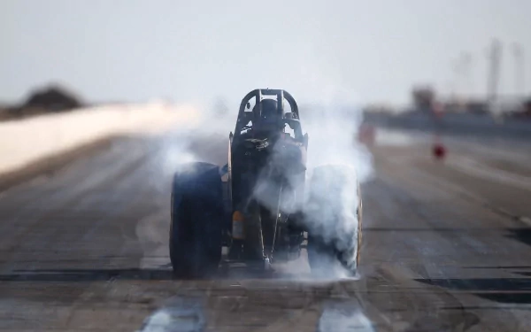 Rear view of a dragster vehicle launching amid tire smoke on a drag strip — 2K Quad HD PC desktop wallpaper/background.