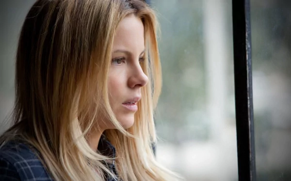 A HD desktop wallpaper featuring a contemplative Kate Beckinsale gazing out a window, showcasing her expressive profile and natural beauty.