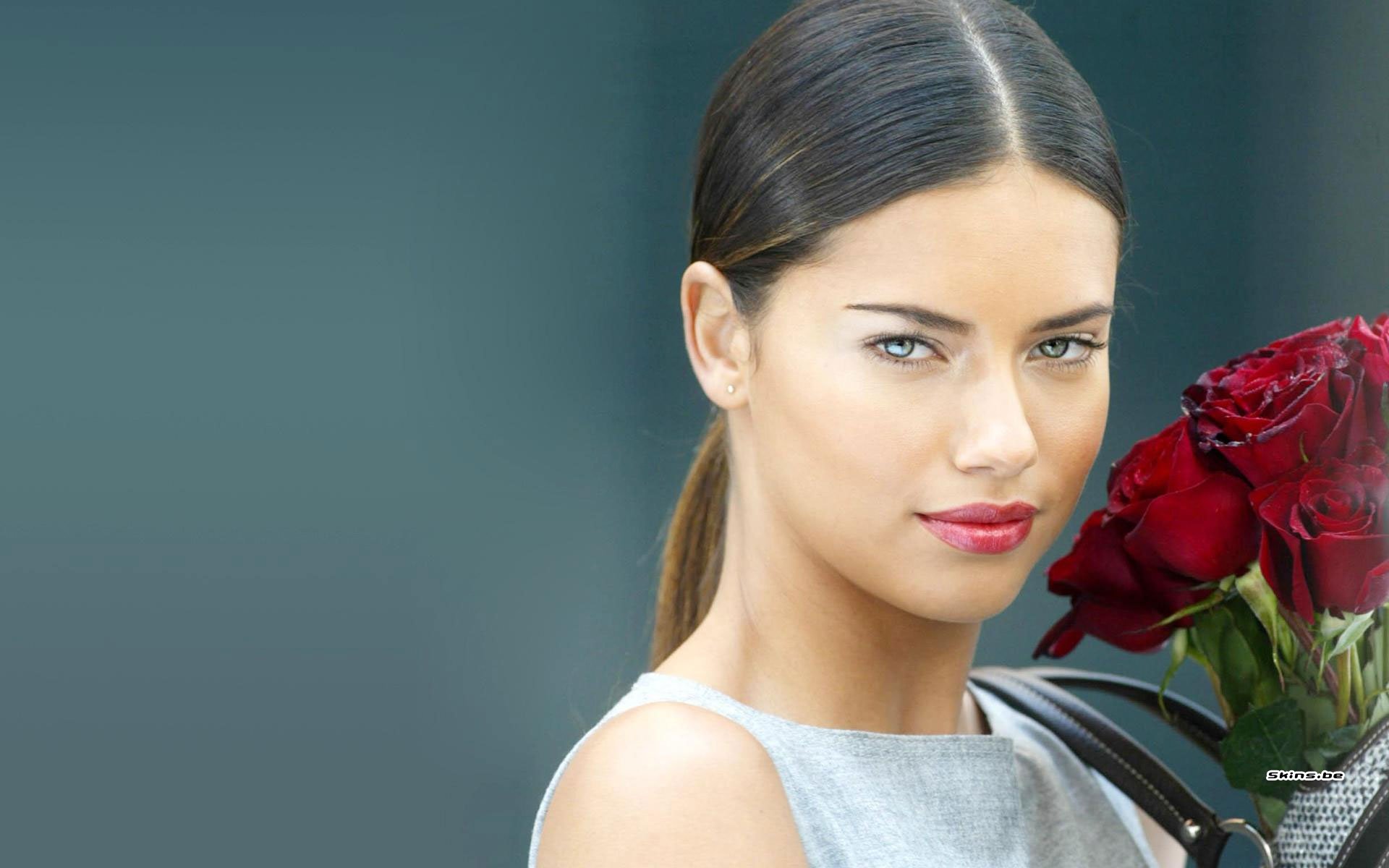 HD PC desktop wallpaper featuring celebrity Adriana Lima holding a bouquet of red roses against a muted blue background.
