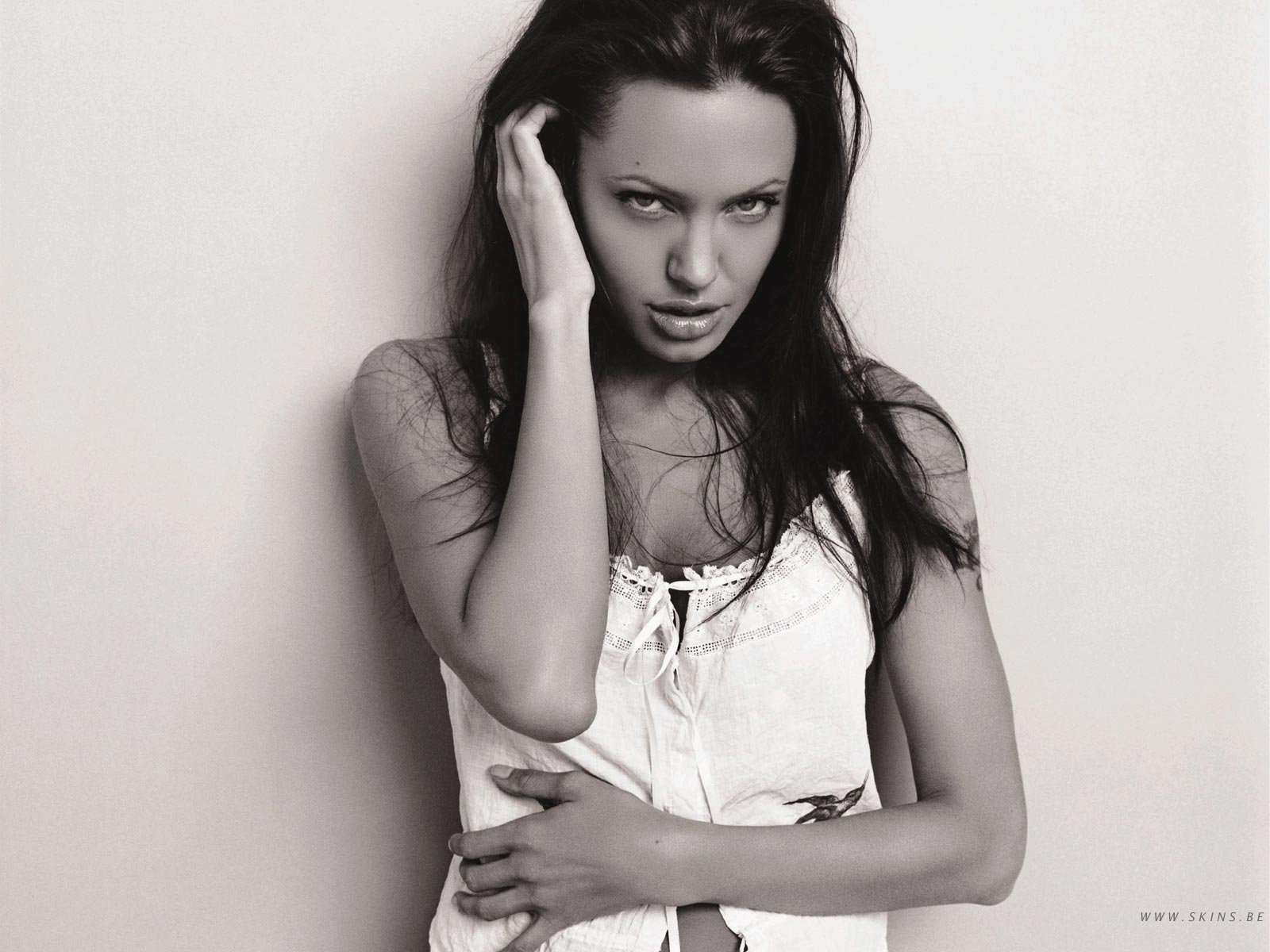 Black and white HD wallpaper featuring Angelina Jolie, capturing her striking expression and elegant pose against a minimalistic background.