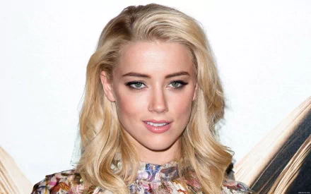 HD desktop wallpaper featuring a close-up of Amber Heard, showcasing her stylish look with flowing blonde hair and striking makeup.