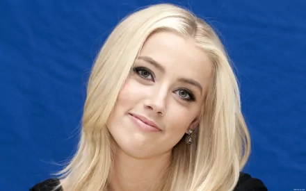 A high-definition desktop wallpaper featuring Amber Heard, showcasing her with a soft smile against a vibrant blue background.