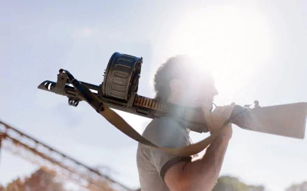 HD desktop wallpaper showing a man carrying a man-made shotgun with a drum magazine against a bright sky background.