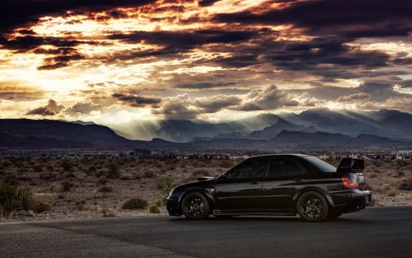 A black Subaru vehicle parked on a desert road under a dramatic, colorful sunset sky, captured in HD for a striking desktop wallpaper background.