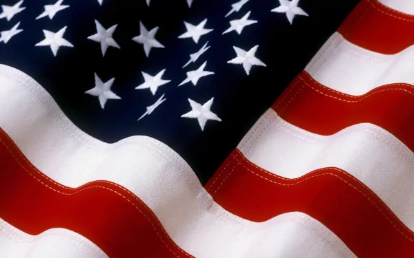 An HD desktop wallpaper featuring a close-up of the American flag, showcasing its vibrant red, white, and blue colors with distinctly visible stars and stripes.