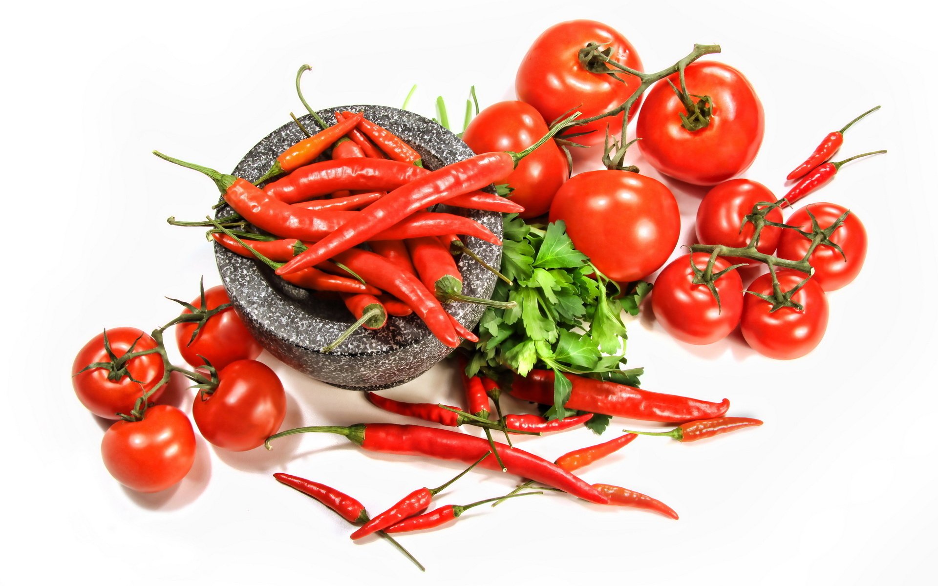 HD desktop wallpaper featuring vibrant red chili peppers, ripe tomatoes, and fresh green herbs arranged on a white background, highlighting fresh food ingredients.
