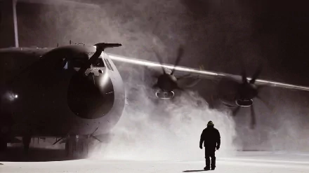 Military Airbus A400M aircraft stands on a foggy runway with a lone figure nearby, captured in a dramatic HD desktop wallpaper.