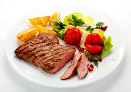 HD PC desktop wallpaper and background of a food meal: grilled steak slices with roasted potato wedges, cherry tomatoes and mixed greens on a white plate.