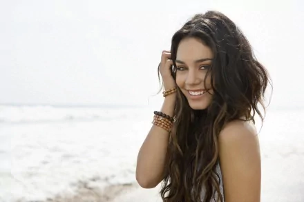 Vanessa Hudgens smiles at the beach, her long hair flowing in the wind, capturing a carefree moment. This stunning image serves as an HD desktop wallpaper and background.