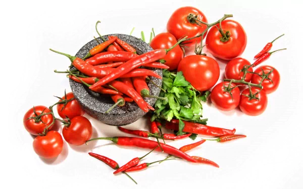 HD desktop wallpaper featuring vibrant red chili peppers, ripe tomatoes, and fresh green herbs arranged on a white background, highlighting fresh food ingredients.