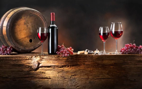 HD PC desktop wallpaper featuring a rustic wooden table with a wine barrel, a bottle of red wine, three filled glasses, and bunches of grapes against a dark background.