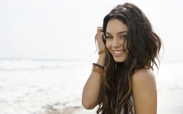 Vanessa Hudgens smiles at the beach, her long hair flowing in the wind, capturing a carefree moment. This stunning image serves as an HD desktop wallpaper and background.