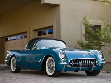 HD PC desktop wallpaper/background: teal Chevrolet Corvette vehicle parked before a garage, glossy curves, chrome grille and whitewall tires against a stucco house and shrub.