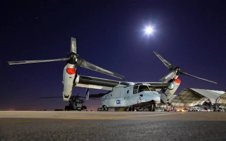 HD desktop wallpaper featuring a Bell Boeing V-22 Osprey military aircraft parked on a runway under a starry night sky.