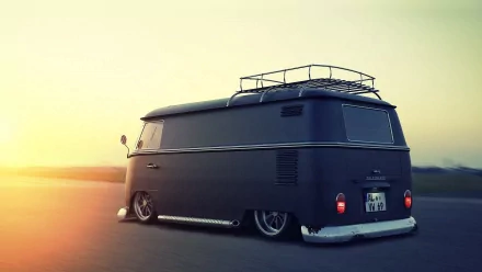A vintage Volkswagen Microbus with a roof rack parked on an open road at sunset, showcasing its sleek design and unique style in this HD desktop wallpaper.