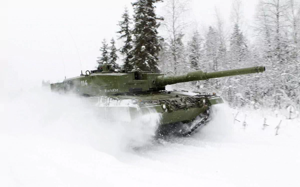 Green Leopard 2 tank powering through deep snow past frost-covered pines — military 2K Quad HD PC desktop wallpaper/background.