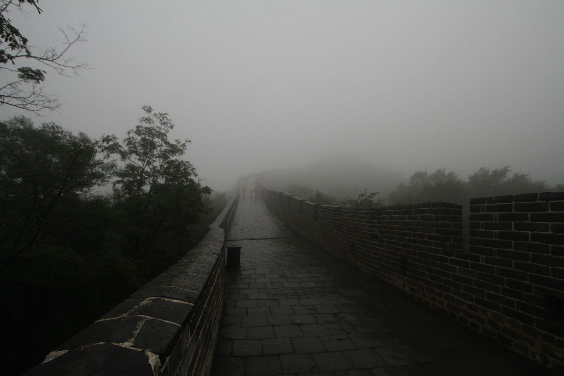 HD PC desktop wallpaper featuring the man-made Great Wall of China disappearing into dense fog, surrounded by misty trees and an overcast sky.
