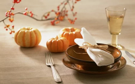 HD PC desktop wallpaper featuring a cozy autumn table setting with small pumpkins, a fork, brown plates, a neatly folded napkin, and a glass of white wine.