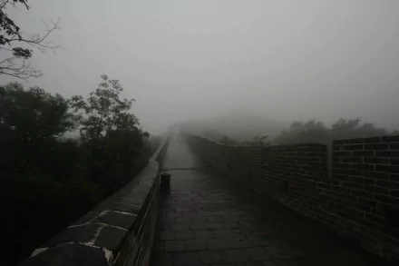 HD PC desktop wallpaper featuring the man-made Great Wall of China disappearing into dense fog, surrounded by misty trees and an overcast sky.