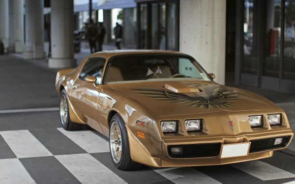 HD PC desktop wallpaper featuring a classic gold Pontiac Trans Am parked on a city street under modern architecture.