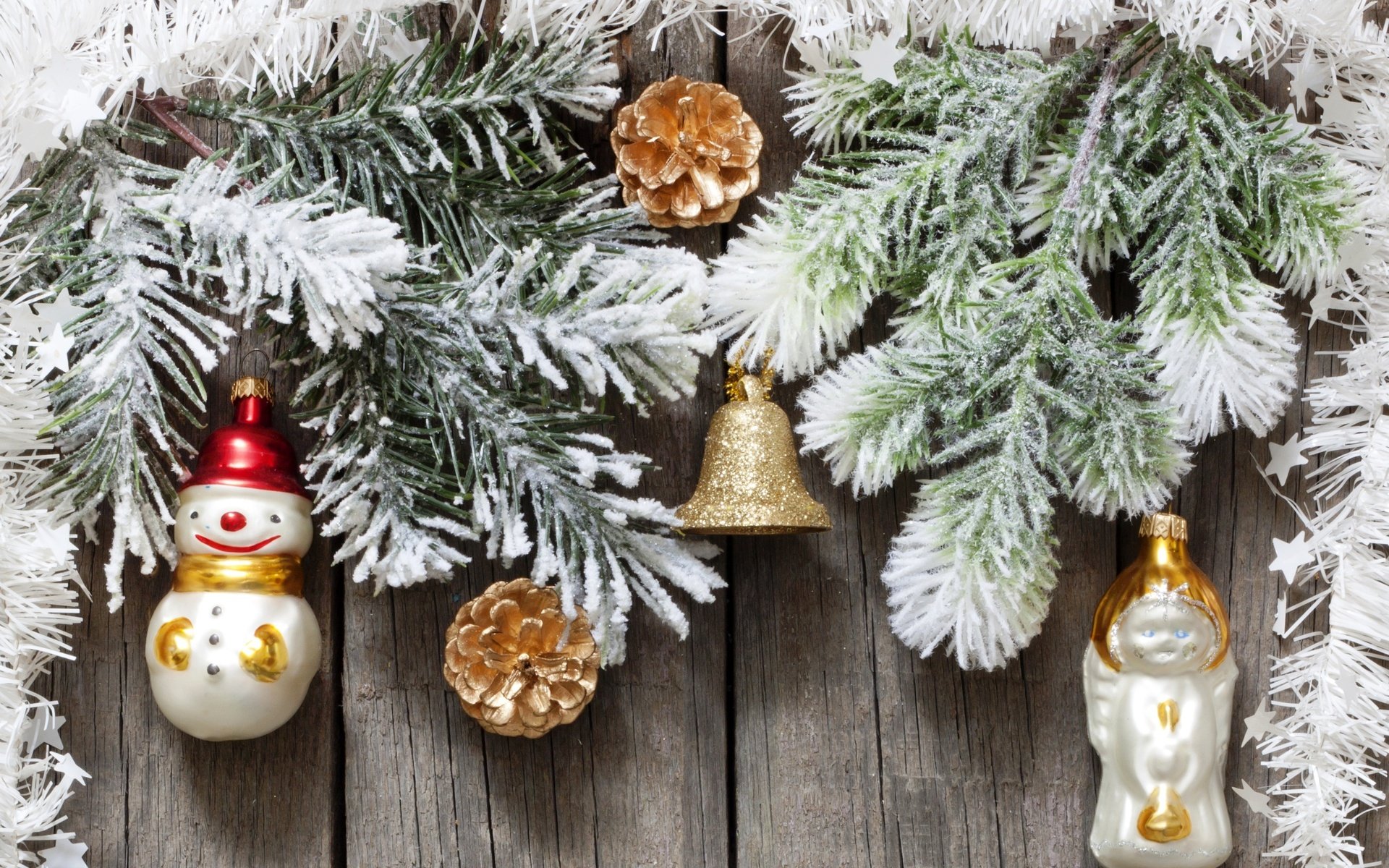 HD desktop wallpaper featuring festive Christmas ornaments, including a snowman, bell, and pinecones, surrounded by snowy evergreen branches, capturing the holiday spirit.